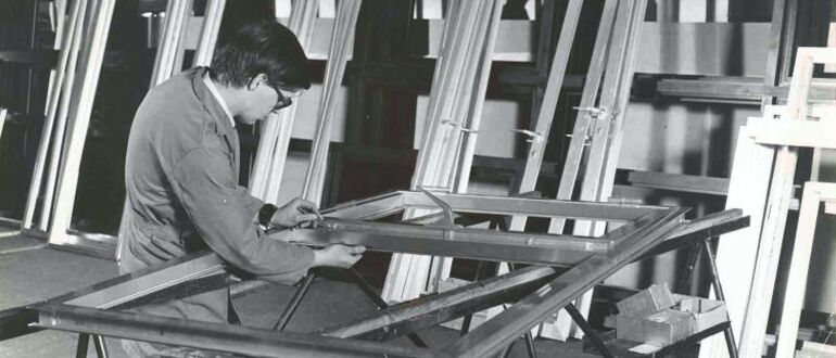 Black-and-white photo of fabricator assembling aluminium window.