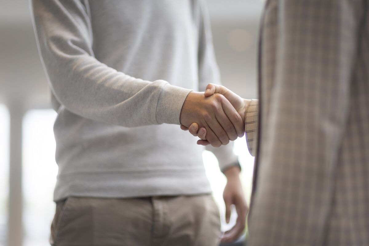 Un homme et une femme se serrent la main dans un immeuble de bureaux.