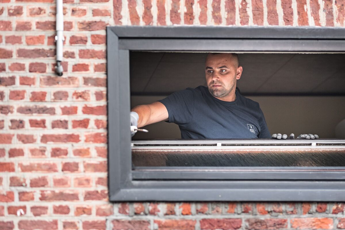 homme installant FENETRE CADRE dans un mur de briques