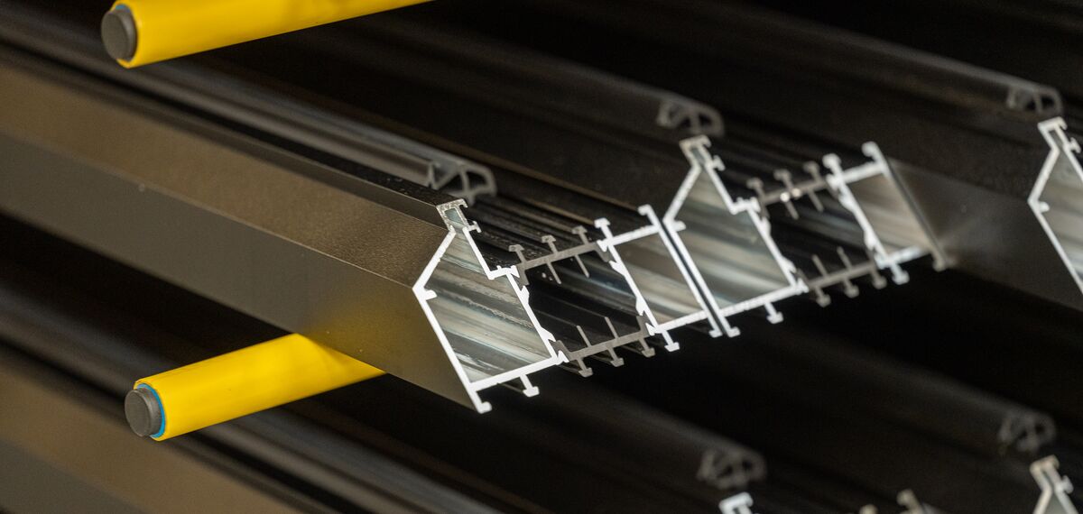 Profilés en aluminium dans un rack jaune.