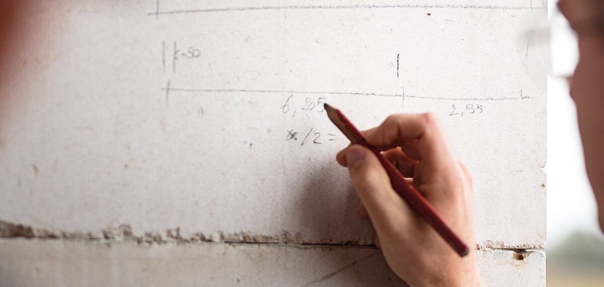 Un homme écrit au crayon sur le mur en béton d'un chantier de construction.