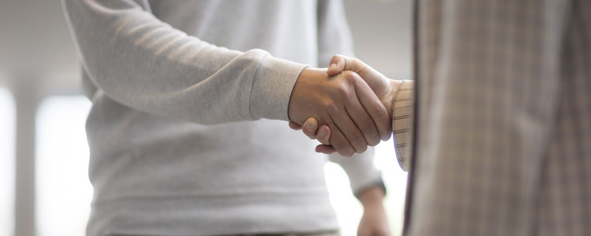 Un homme et une femme se serrent la main dans un immeuble de bureaux.