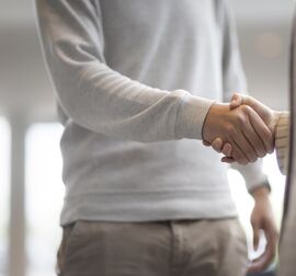 Un homme et une femme se serrent la main dans un immeuble de bureaux.