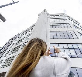 Femme blonde devant un immeuble blanc de taille moyenne en ville