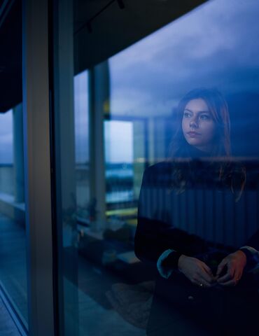 Femme regardant hors de FENETRE à la tombée de la nuit.