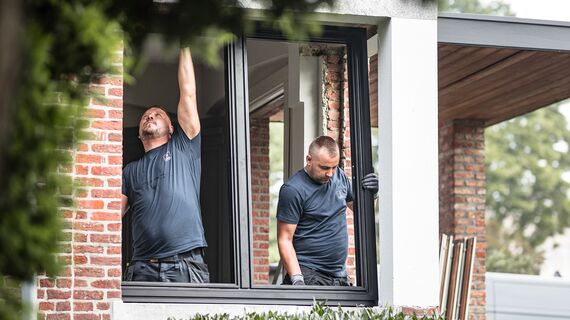 Deux installateurs posant de nouveaux profils en aluminium dans une maison rénovée.